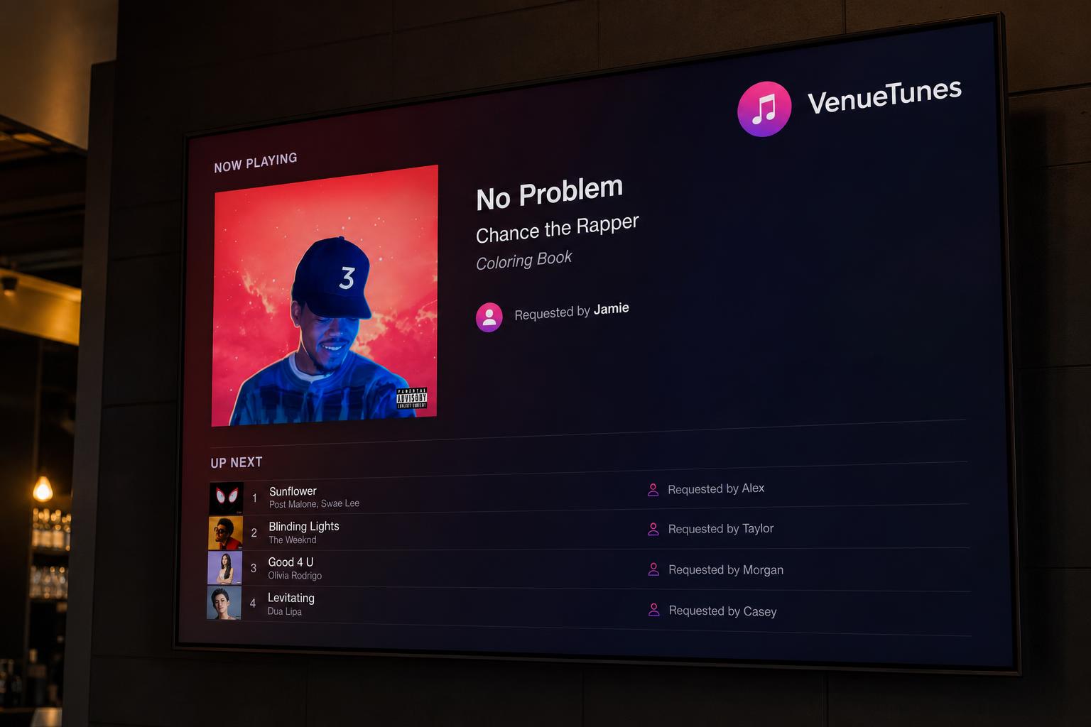 Branded VenueTunes display screen mounted on a wood wall.